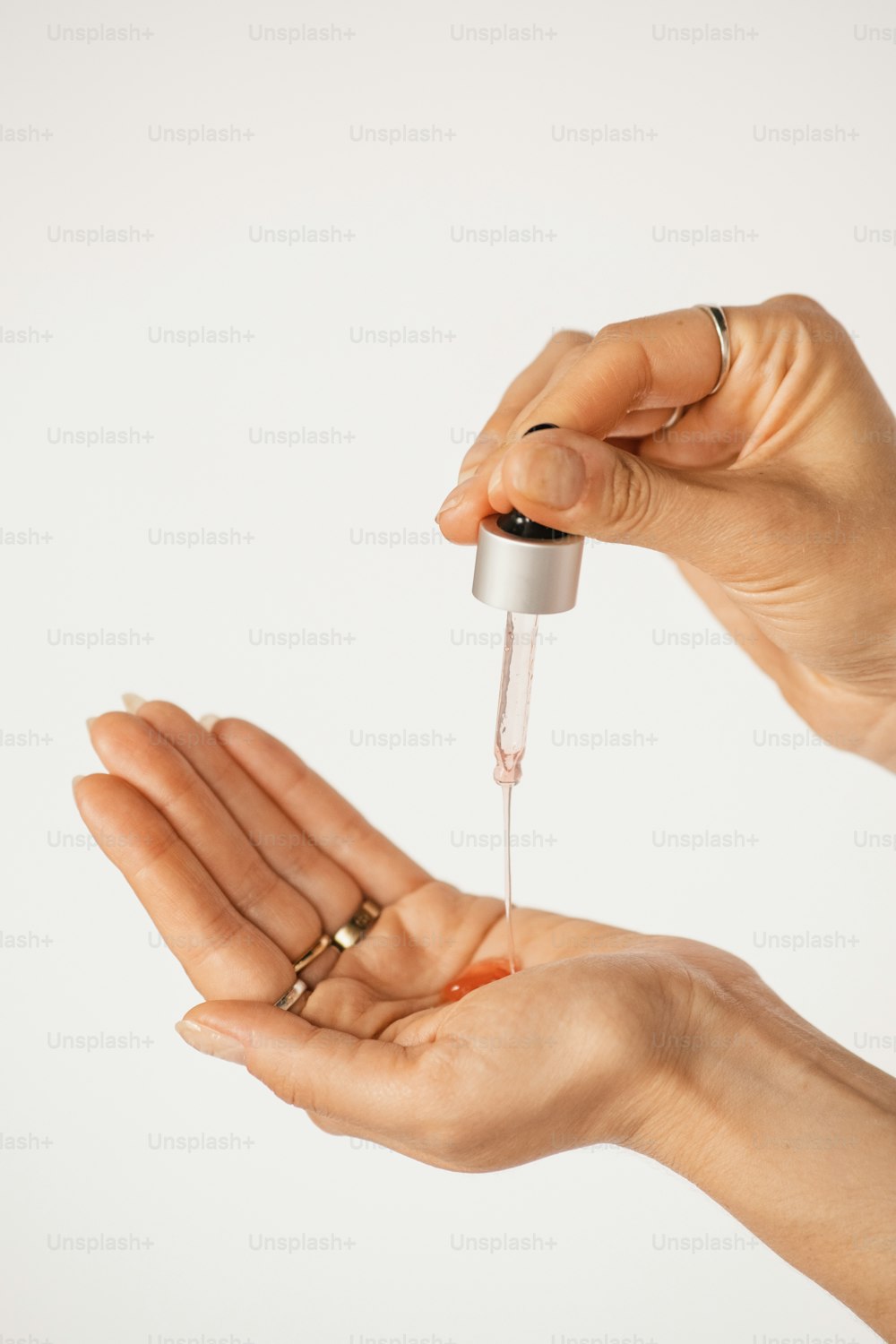 two hands holding a small bottle of liquid