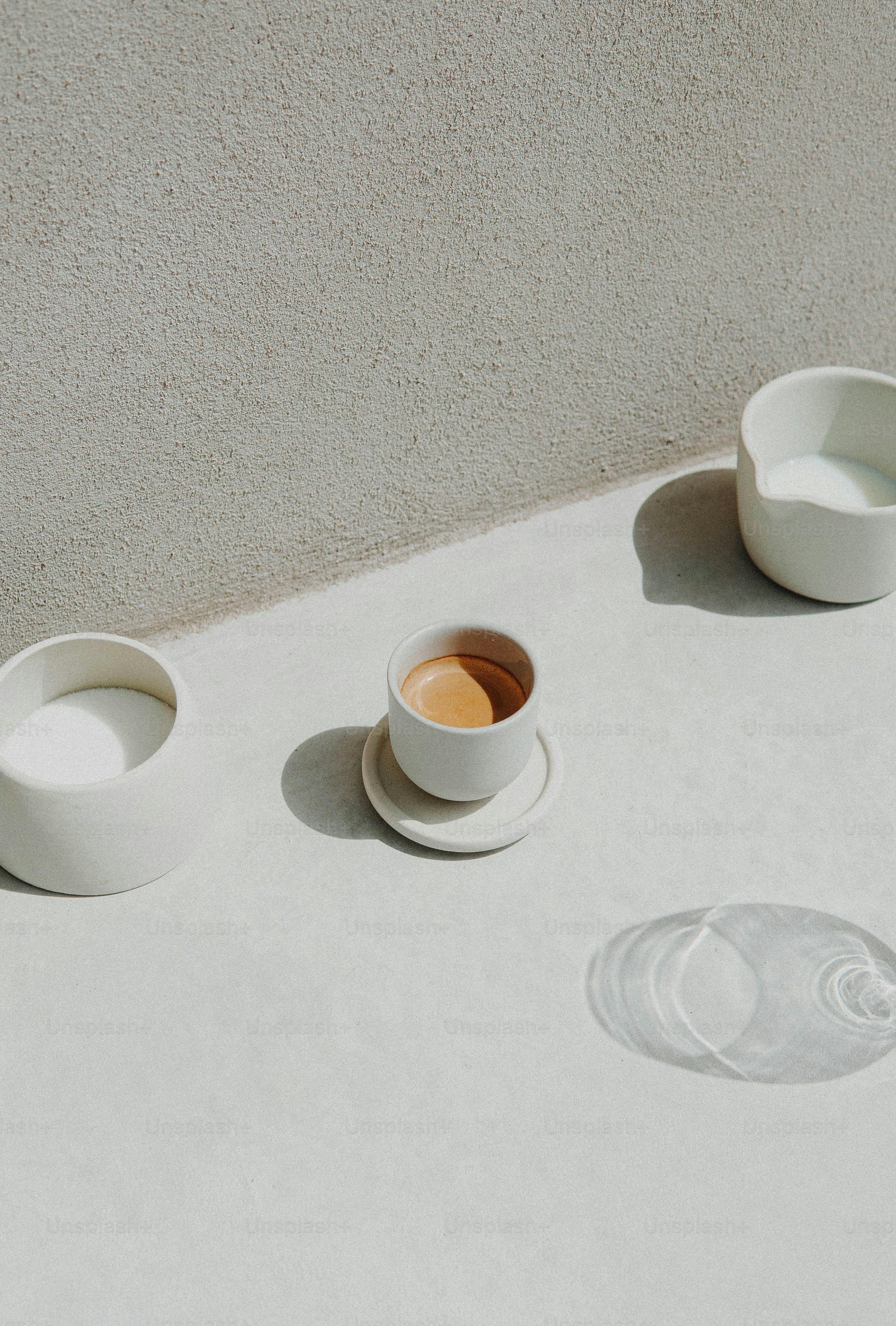 a table topped with white bowls and cups