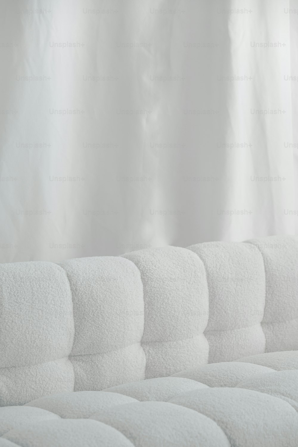 a close up of a white couch with a curtain in the background