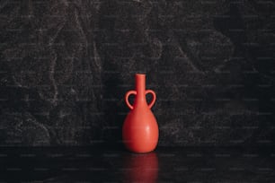 a red vase sitting on top of a table
