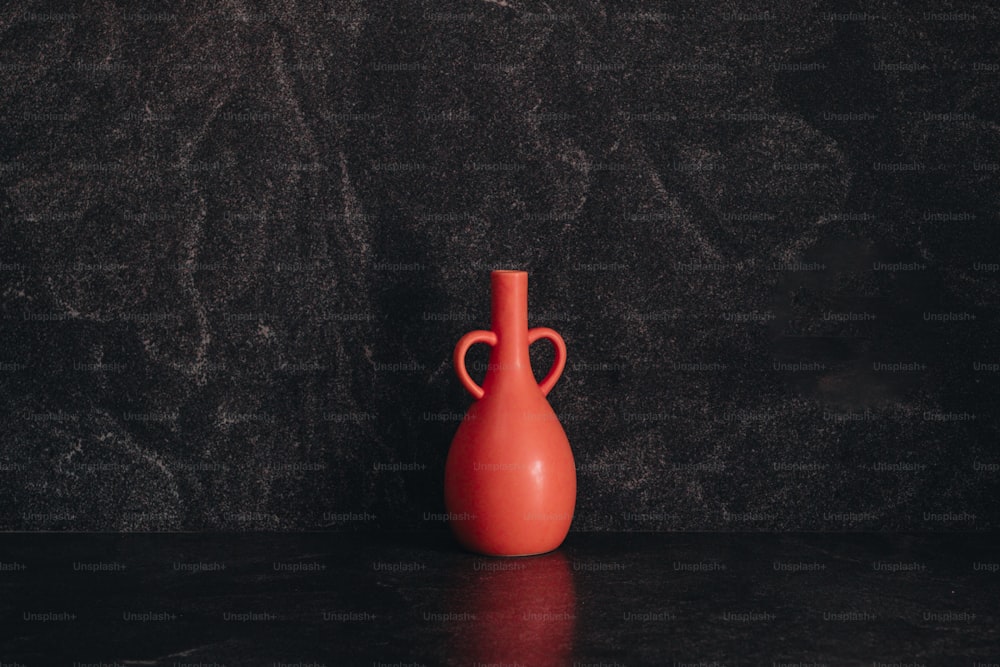 um vaso vermelho sentado em cima de uma mesa