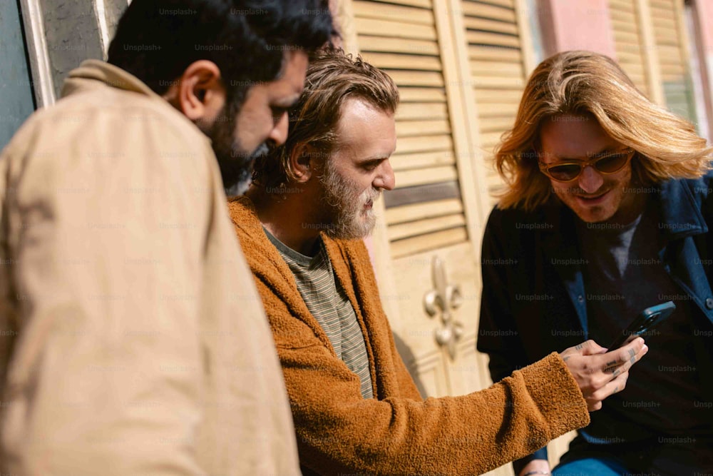 two men and a woman looking at a cell phone