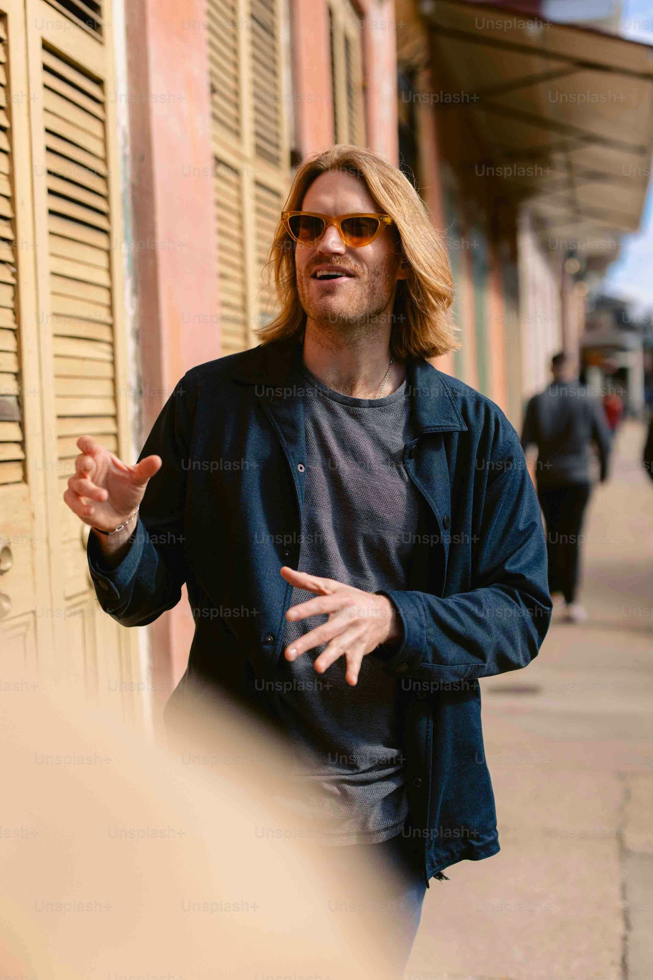 a man in a black jacket and sunglasses talking to someone