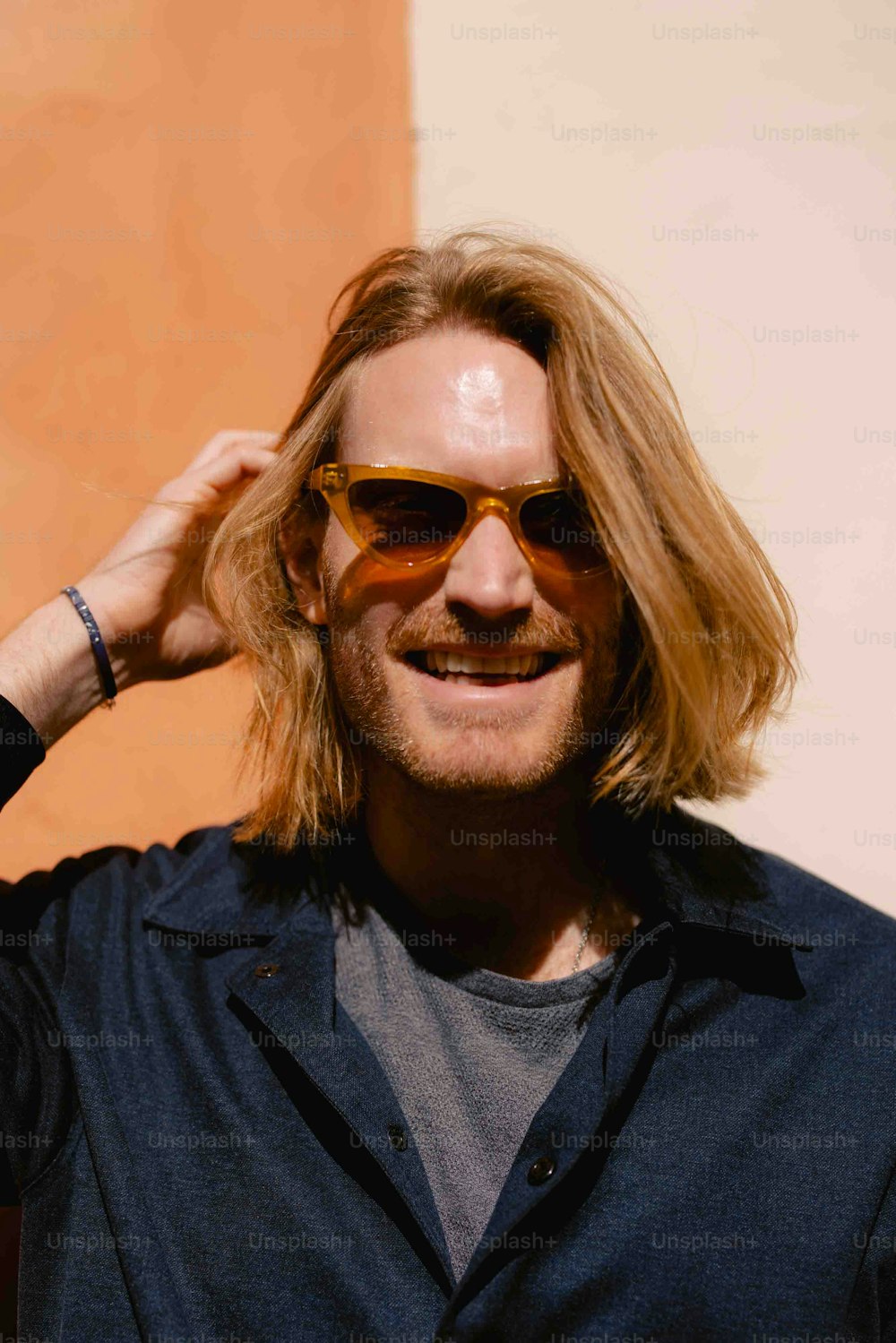 a man with long hair wearing sunglasses and a blue shirt