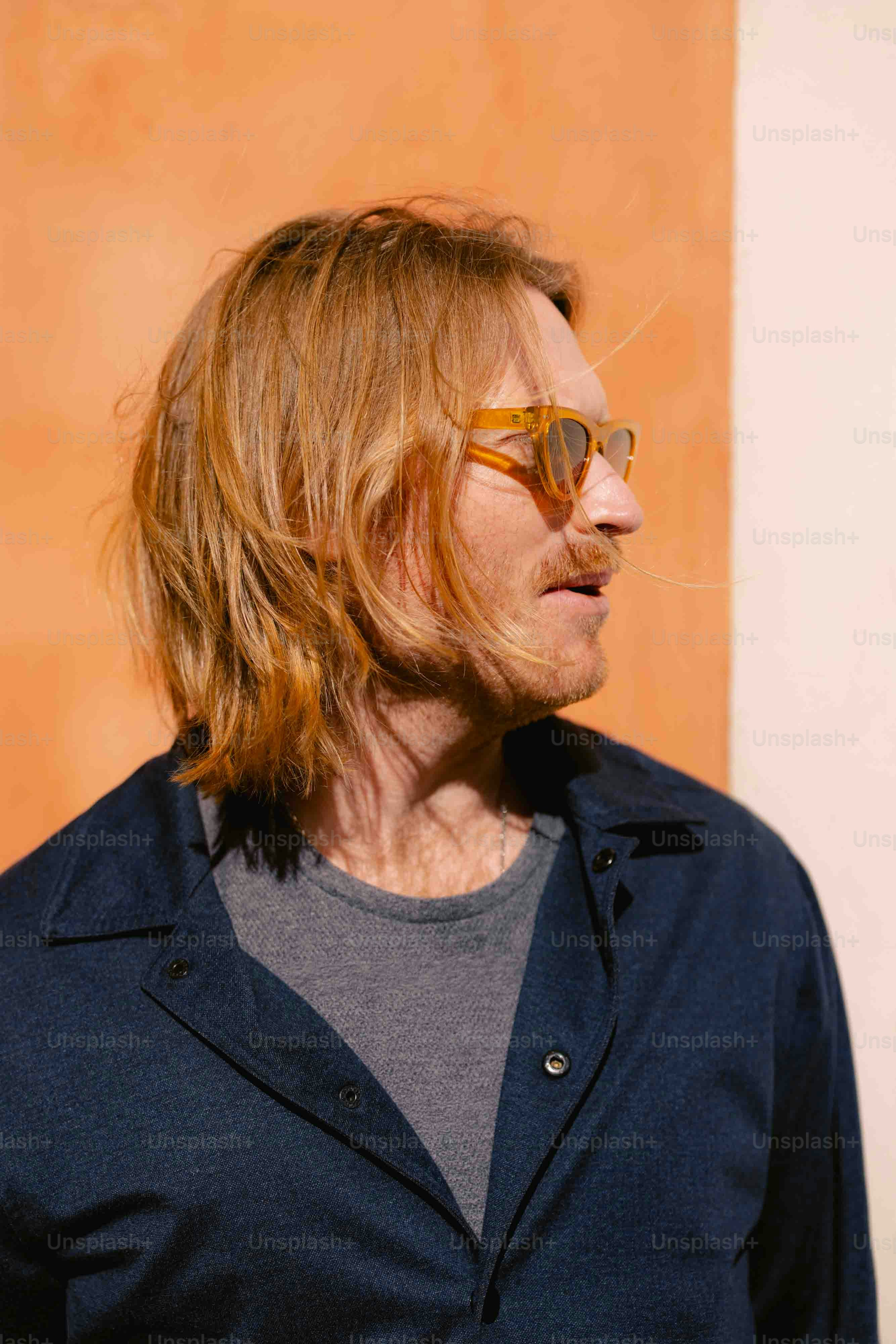 a man with long hair wearing sunglasses and a blue shirt