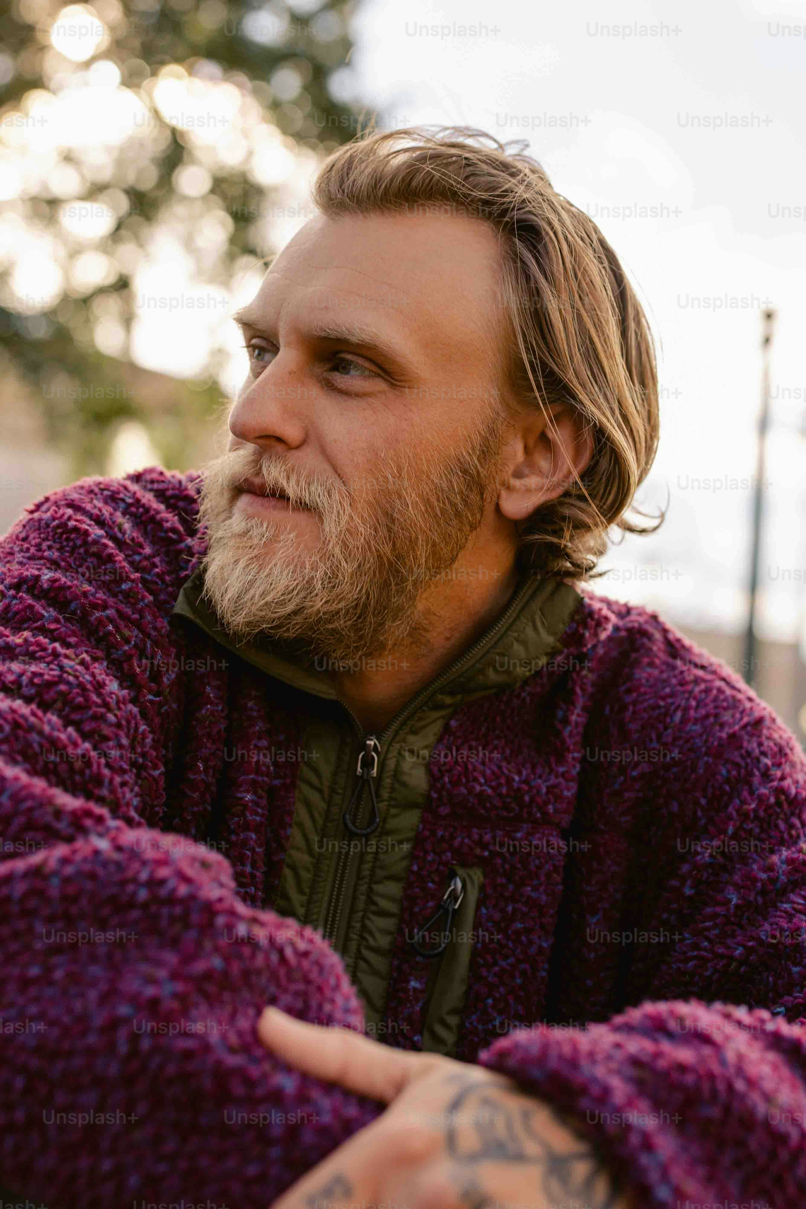 un uomo con i capelli lunghi e la barba che indossa un maglione viola