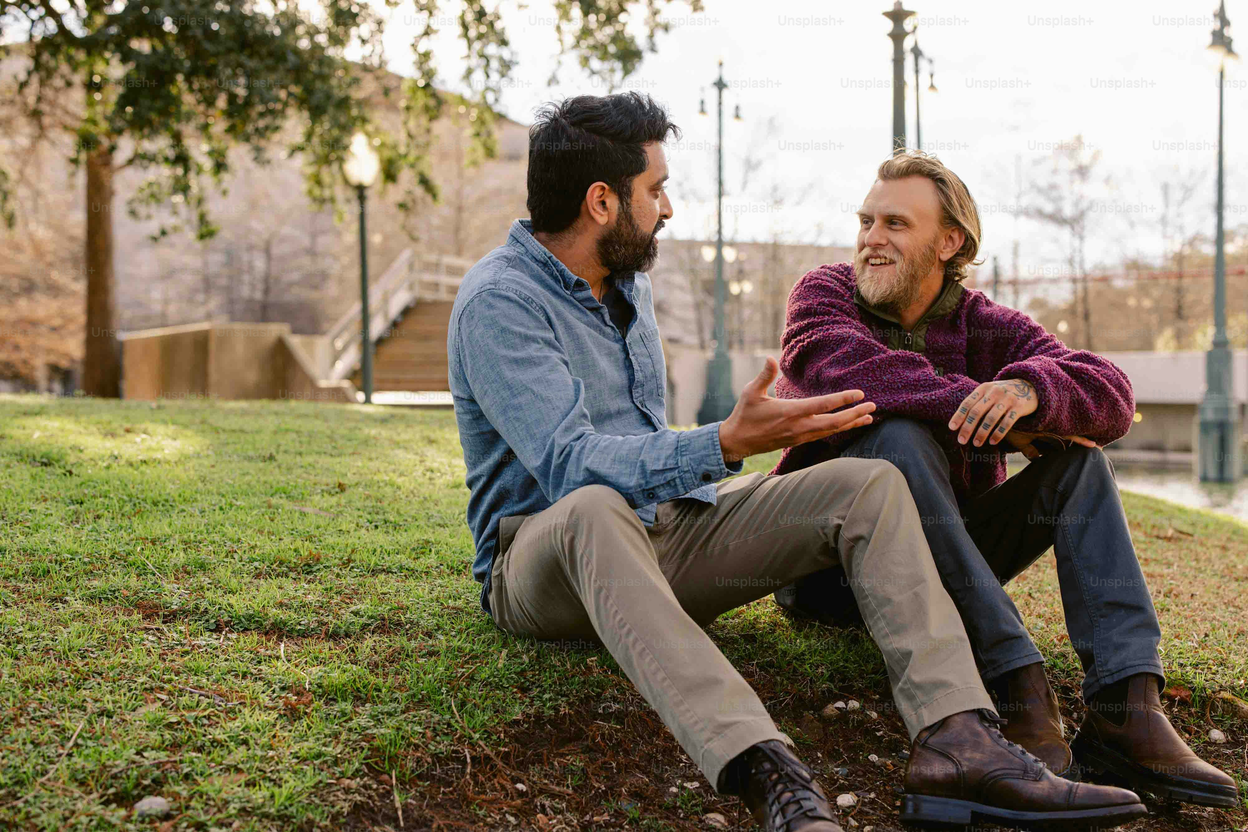 a couple of men sitting on top of a lush green field