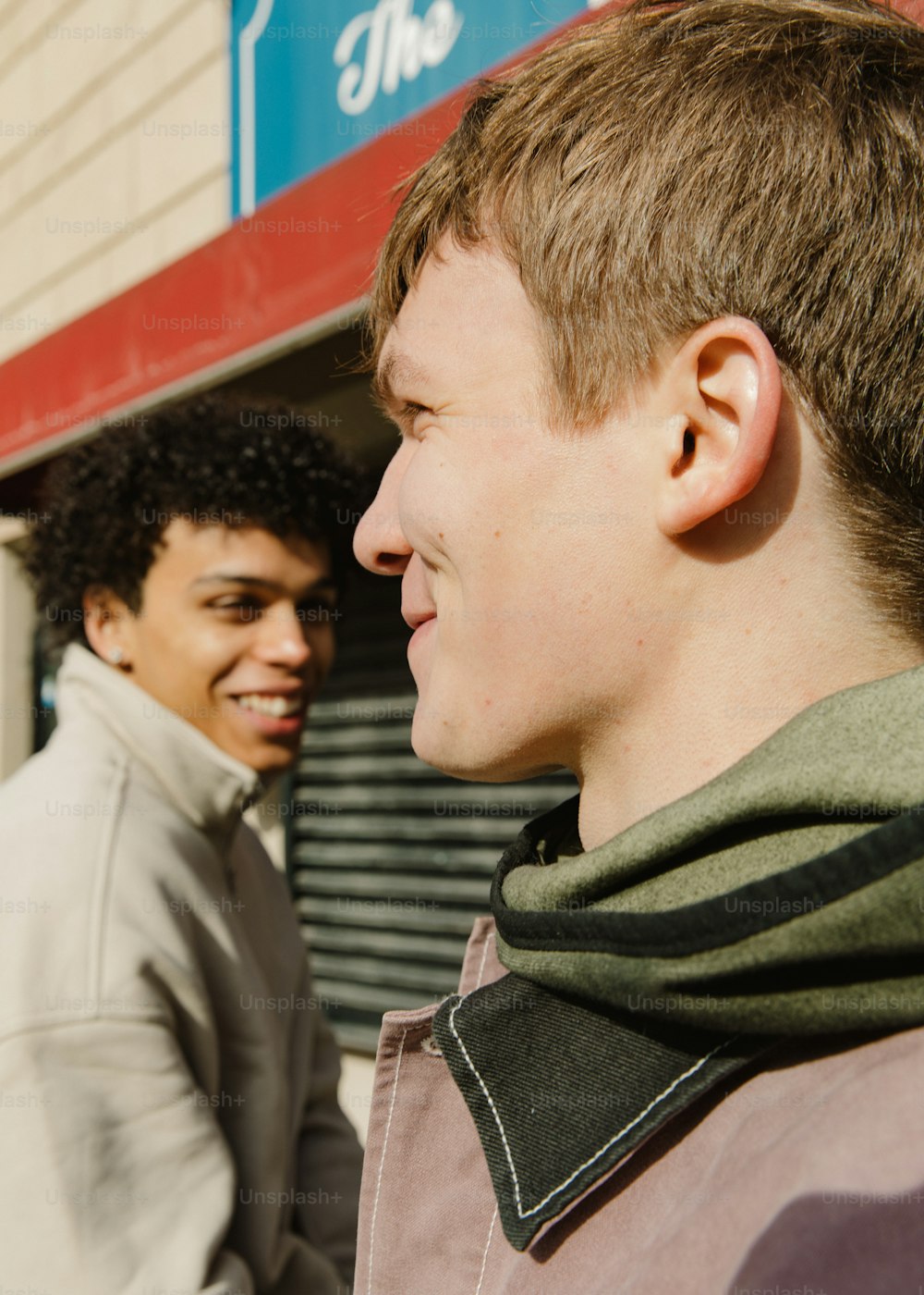 two young men standing next to each other in front of a building