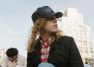 a man with long curly hair wearing a hat