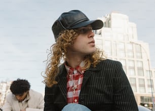 un homme aux longs cheveux bouclés portant un chapeau