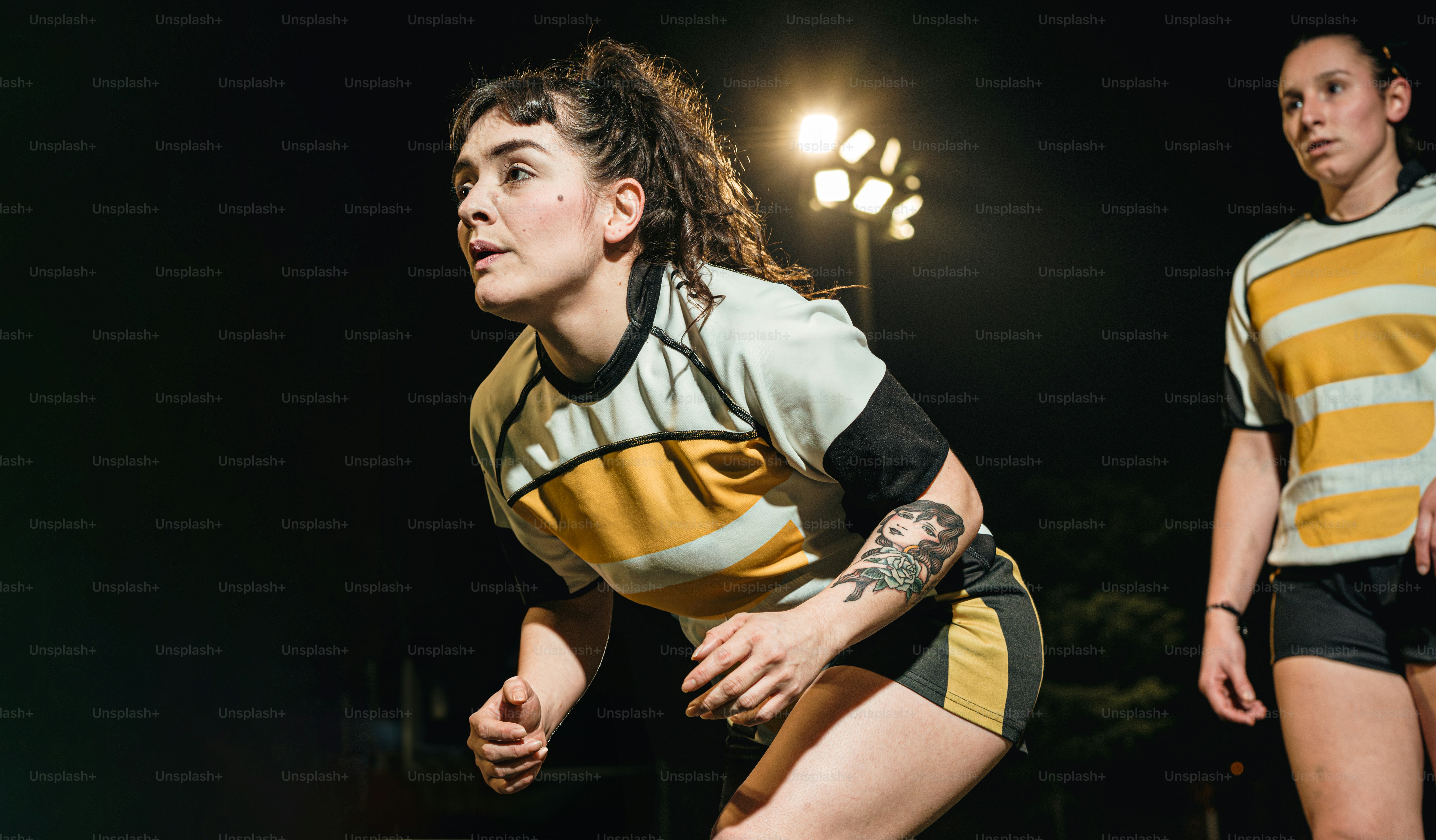 seorang pemain sepak bola wanita berseragam kuning dan hitam