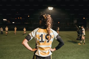 a woman standing on a soccer field with her back to the camera