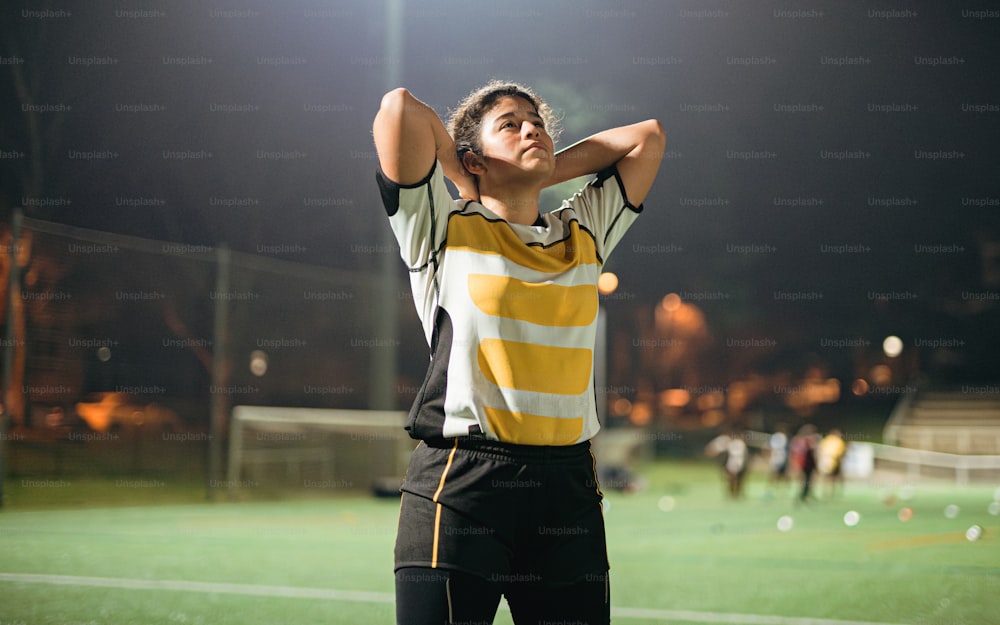 Un homme debout sur un terrain de football tenant ses mains derrière sa tête