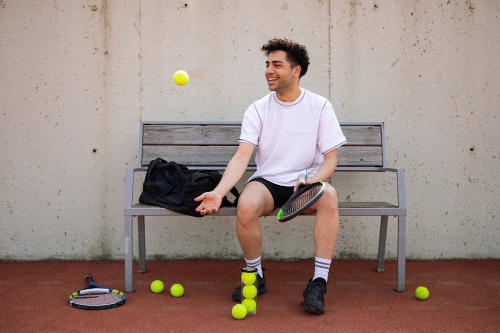a man sitting on a bench with tennis balls in front of him