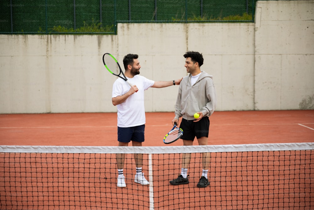 Zwei Männer schütteln sich die Hände über einem Tennisnetz