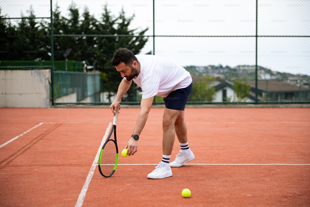 ein Mann, der einen Tennisschläger auf einem Tennisplatz hält