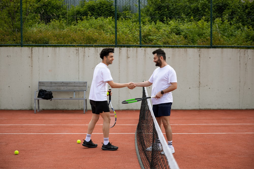 two men shaking hands over a tennis net