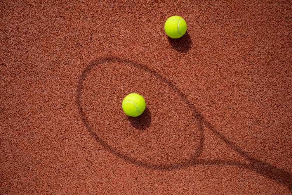 two tennis balls sitting on top of a tennis court