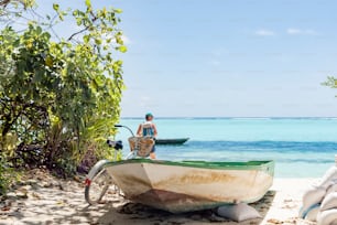 a man standing next to a boat on a beach