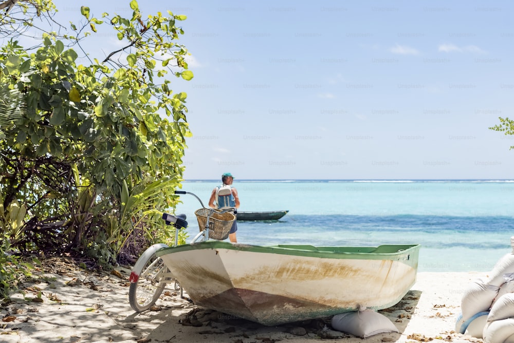 a man standing next to a boat on a beach