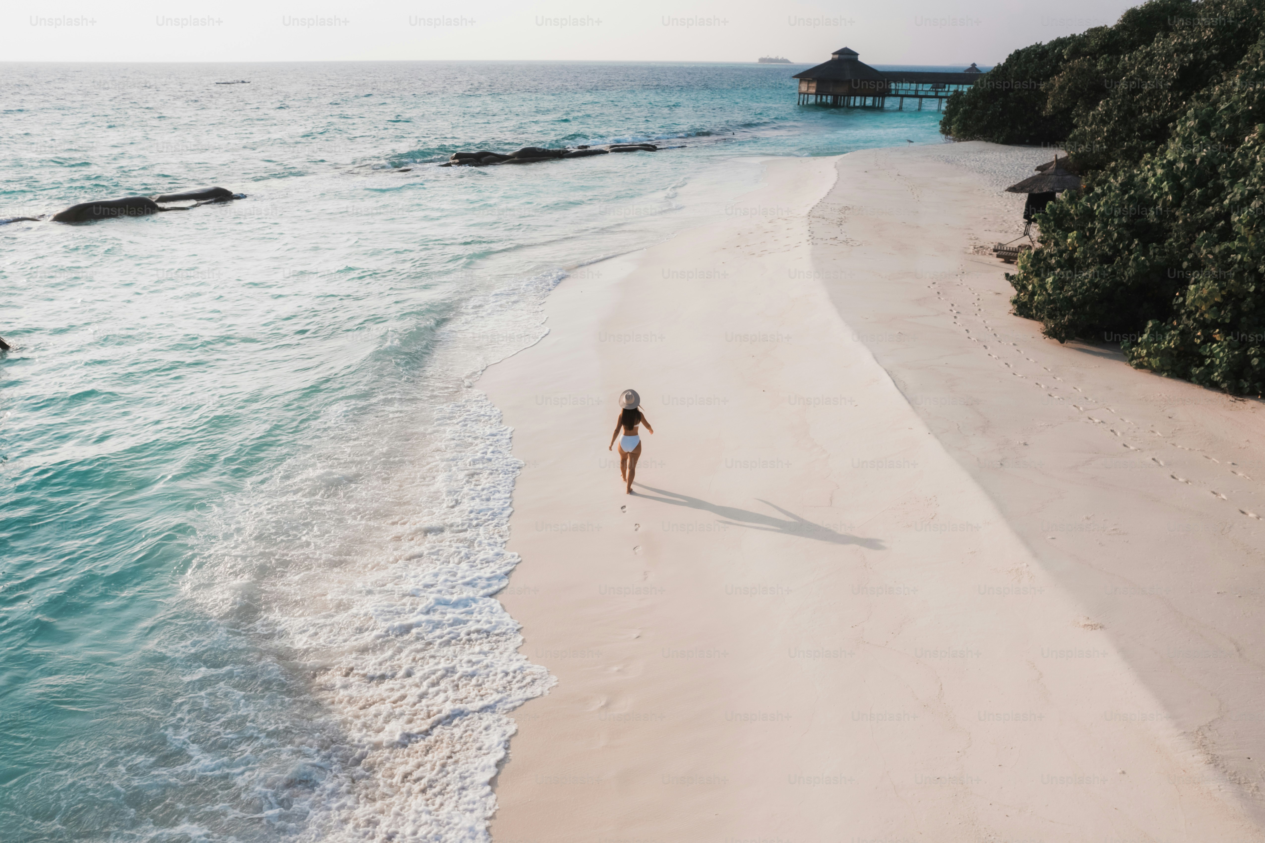 uma mulher caminhando ao longo de uma praia ao lado do oceano