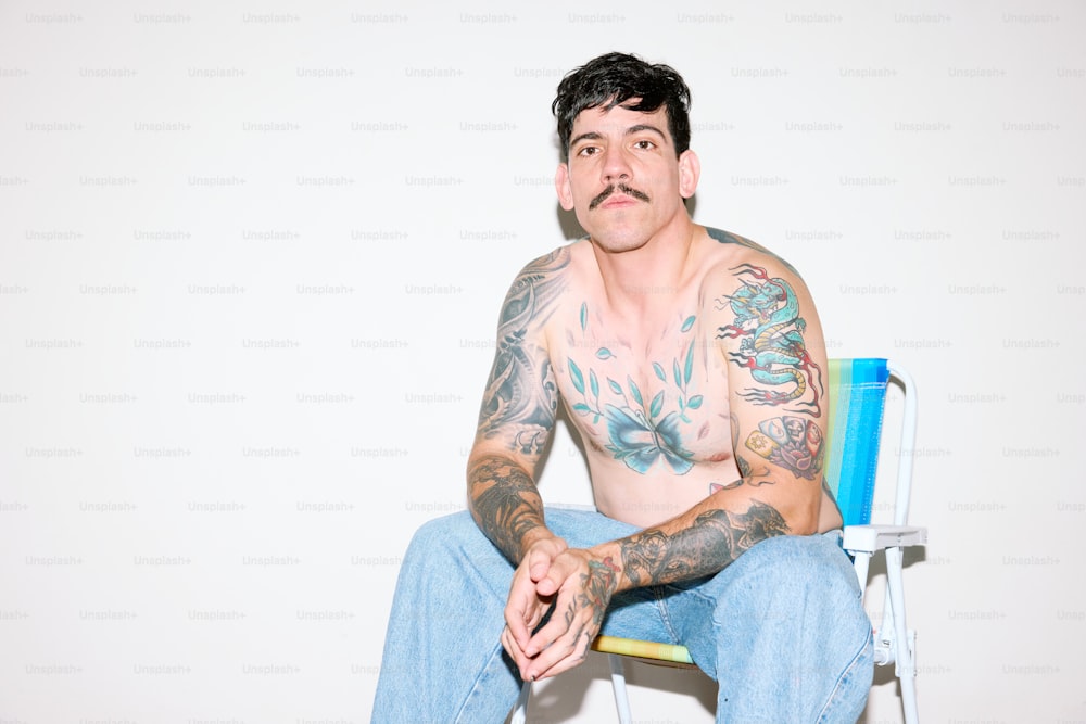 a man with tattoos sitting on a chair