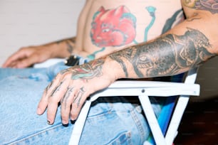 a man with tattoos sitting in a chair