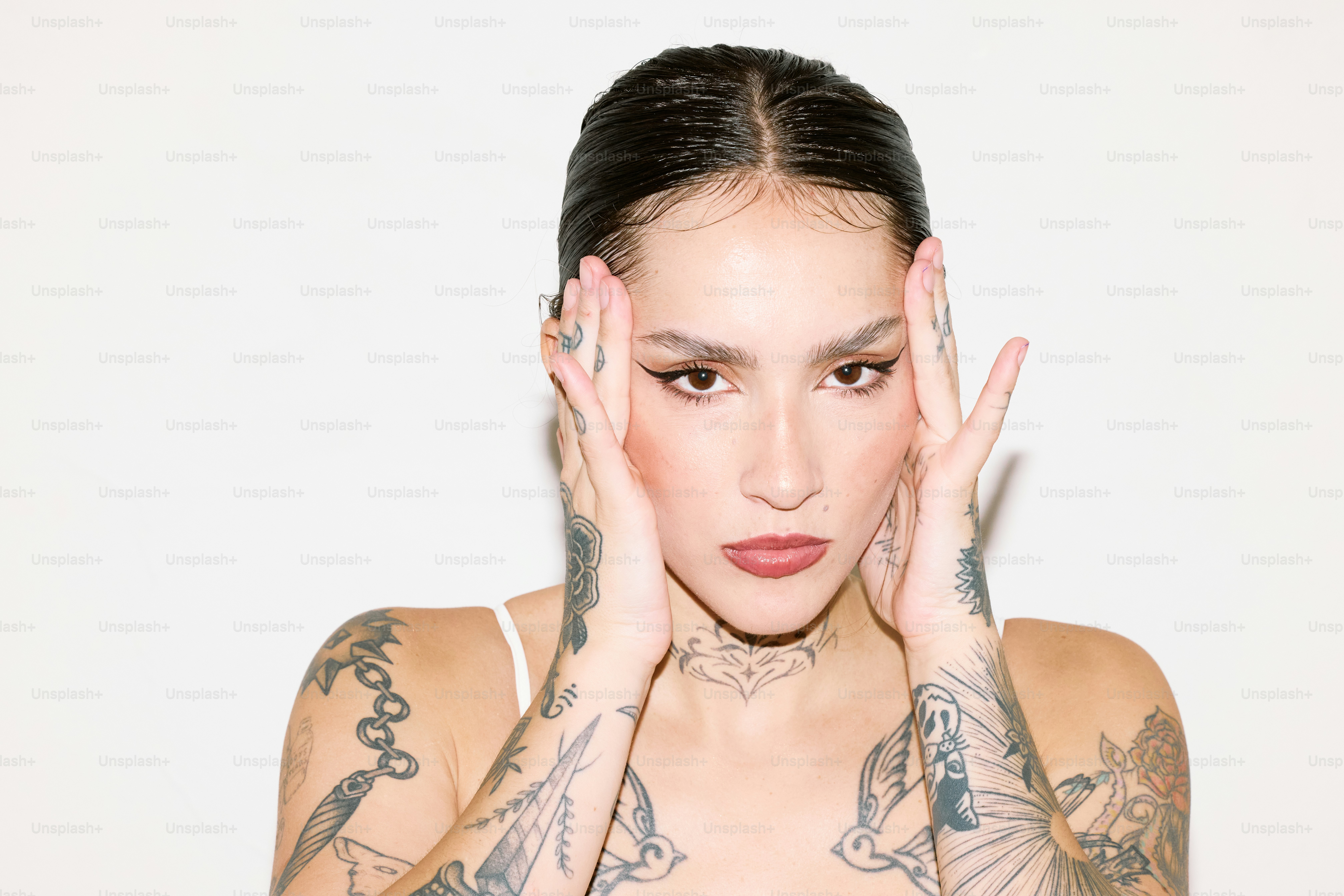 una mujer con tatuajes llevándose las manos a la cara