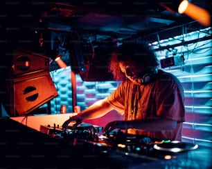 Un homme qui se tient devant la table de mixage d’un DJ
