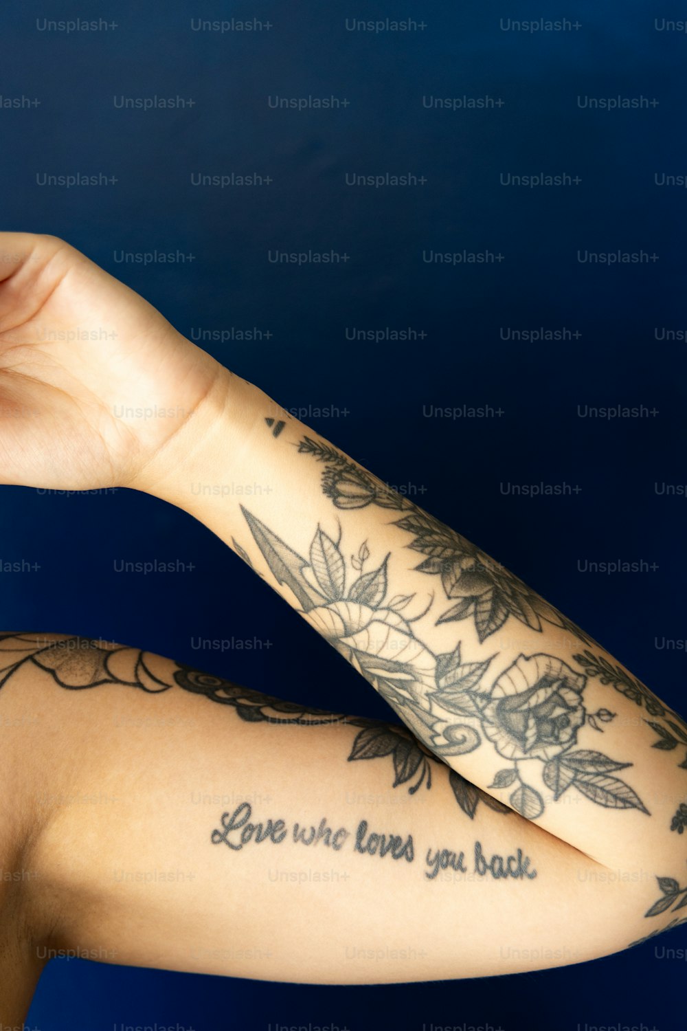 Eine Frau mit einem Tattoo auf dem Arm hält ein Handy in der Hand