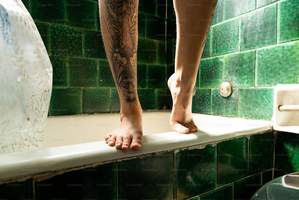 una persona de pie en una repisa en un baño de azulejos verdes