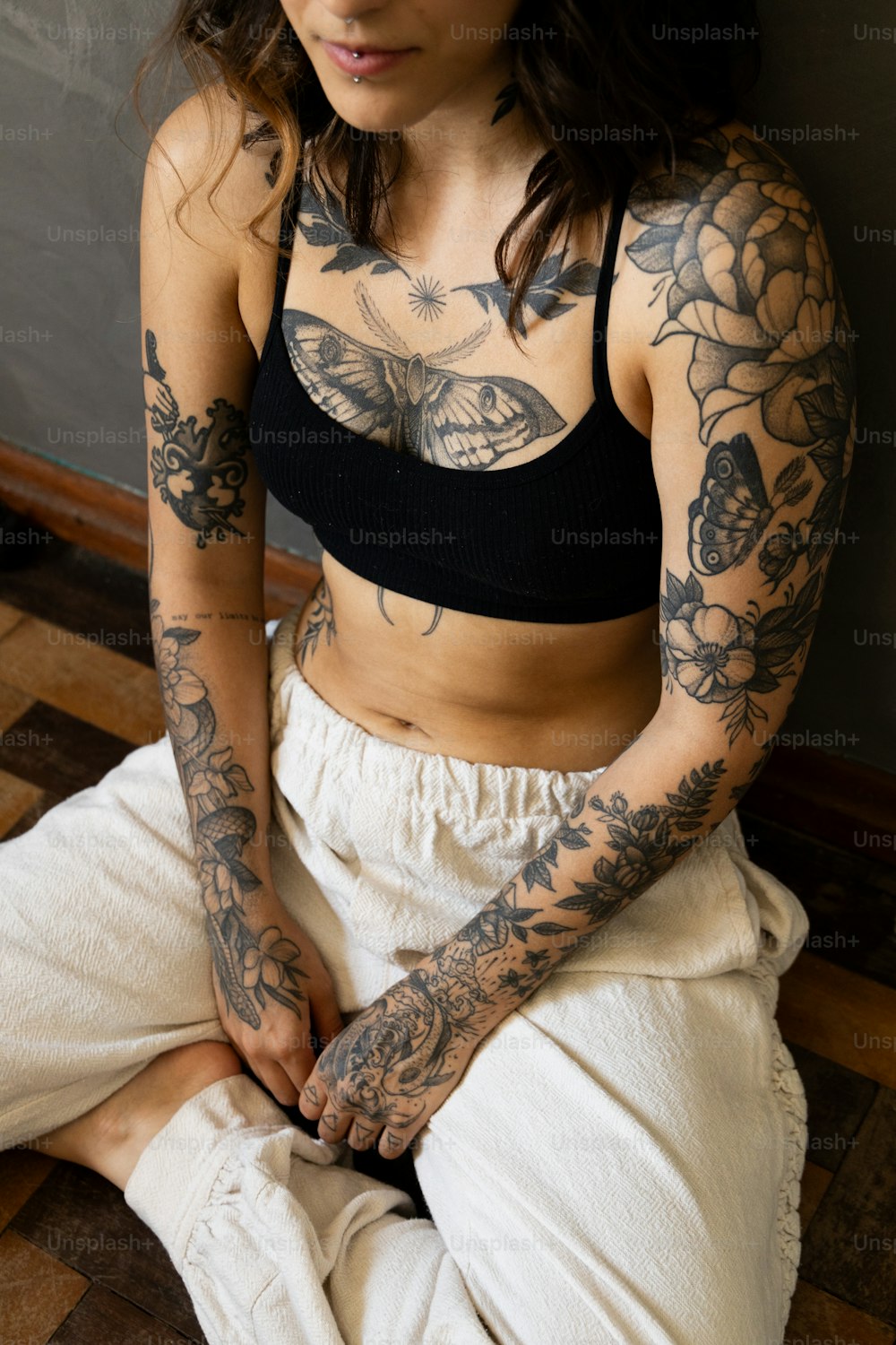 une femme avec des tatouages assise sur le sol