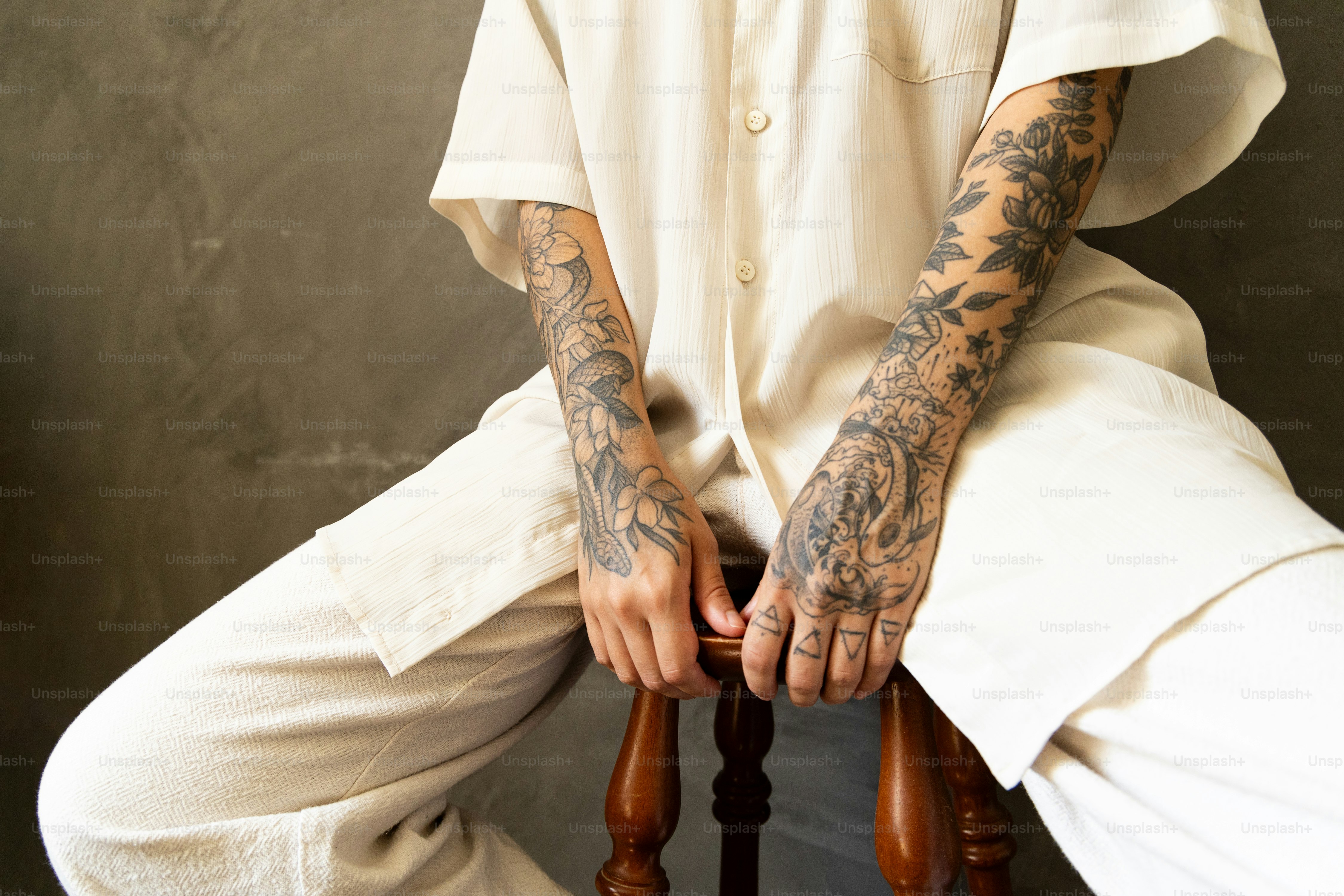 a man with tattoos sitting on a chair