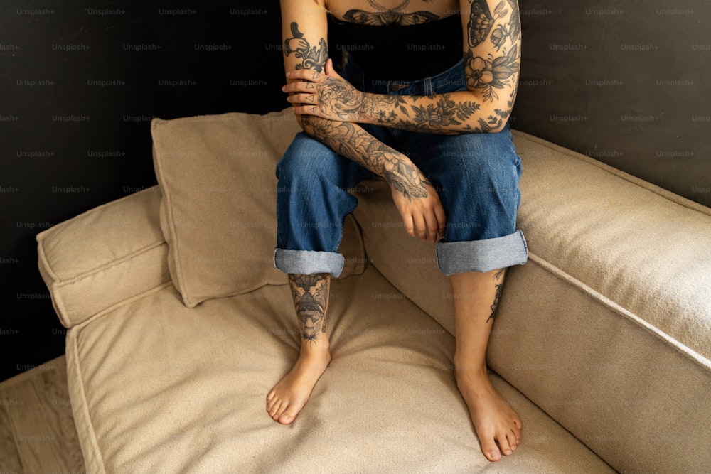 Eine Frau mit Tattoos sitzt auf einer Couch
