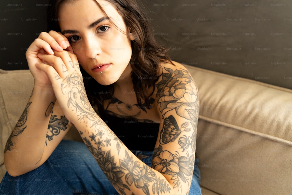 a woman with tattoos sitting on a couch