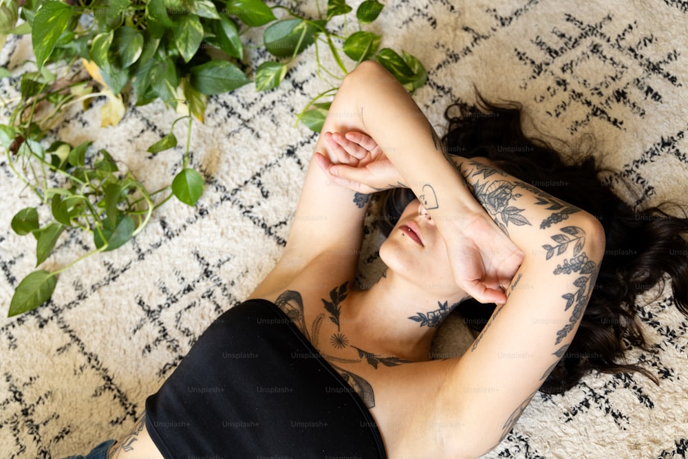 a woman with tattoos laying on a rug