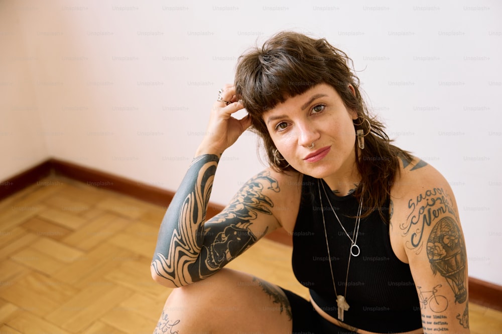 a woman with tattoos sitting on the floor