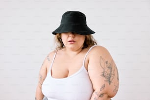 una mujer con una camiseta blanca sin mangas y un sombrero negro