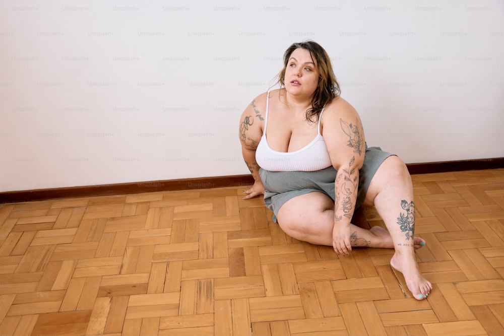 a woman sitting on the floor with a tattoo on her arm