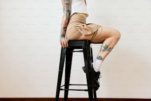 a woman with tattoos sitting on a stool
