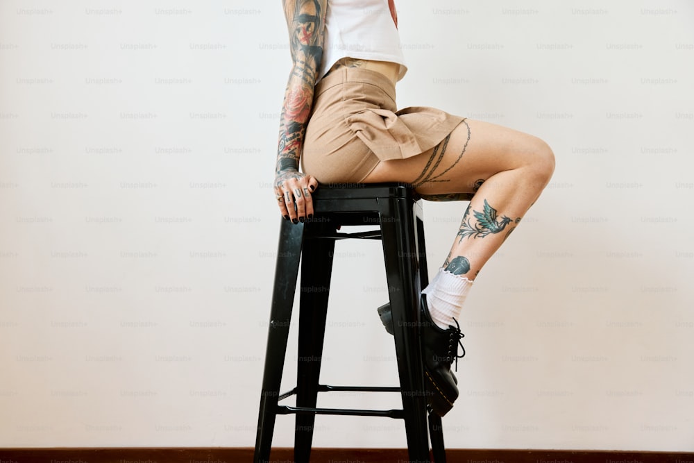 una donna con tatuaggi seduta su uno sgabello