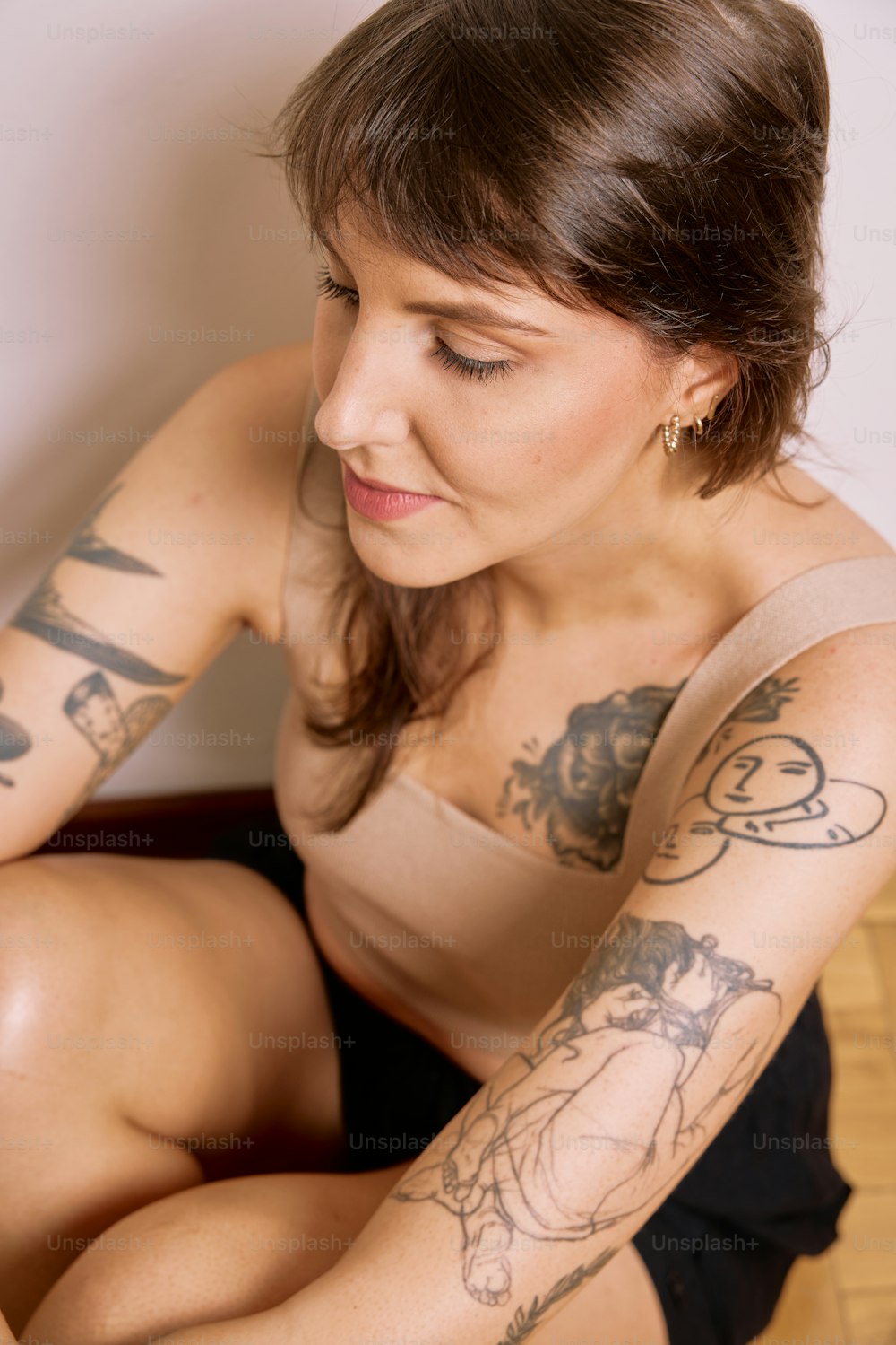 una mujer con tatuajes sentada en el suelo