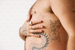 a man with tattoos on his chest holding his hand on his hip
