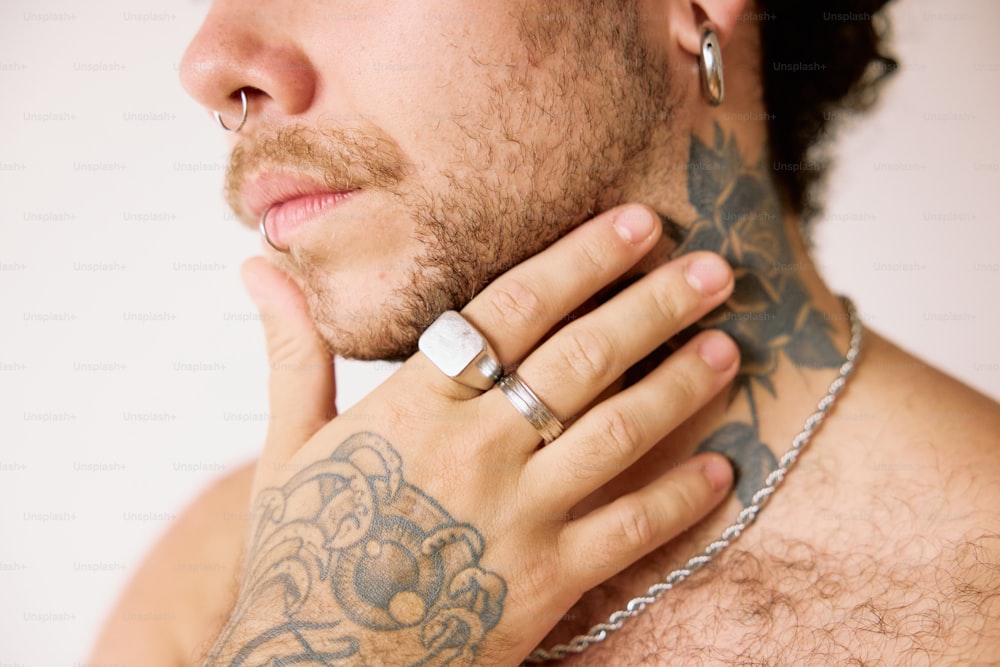 a man with tattoos on his chest wearing a ring