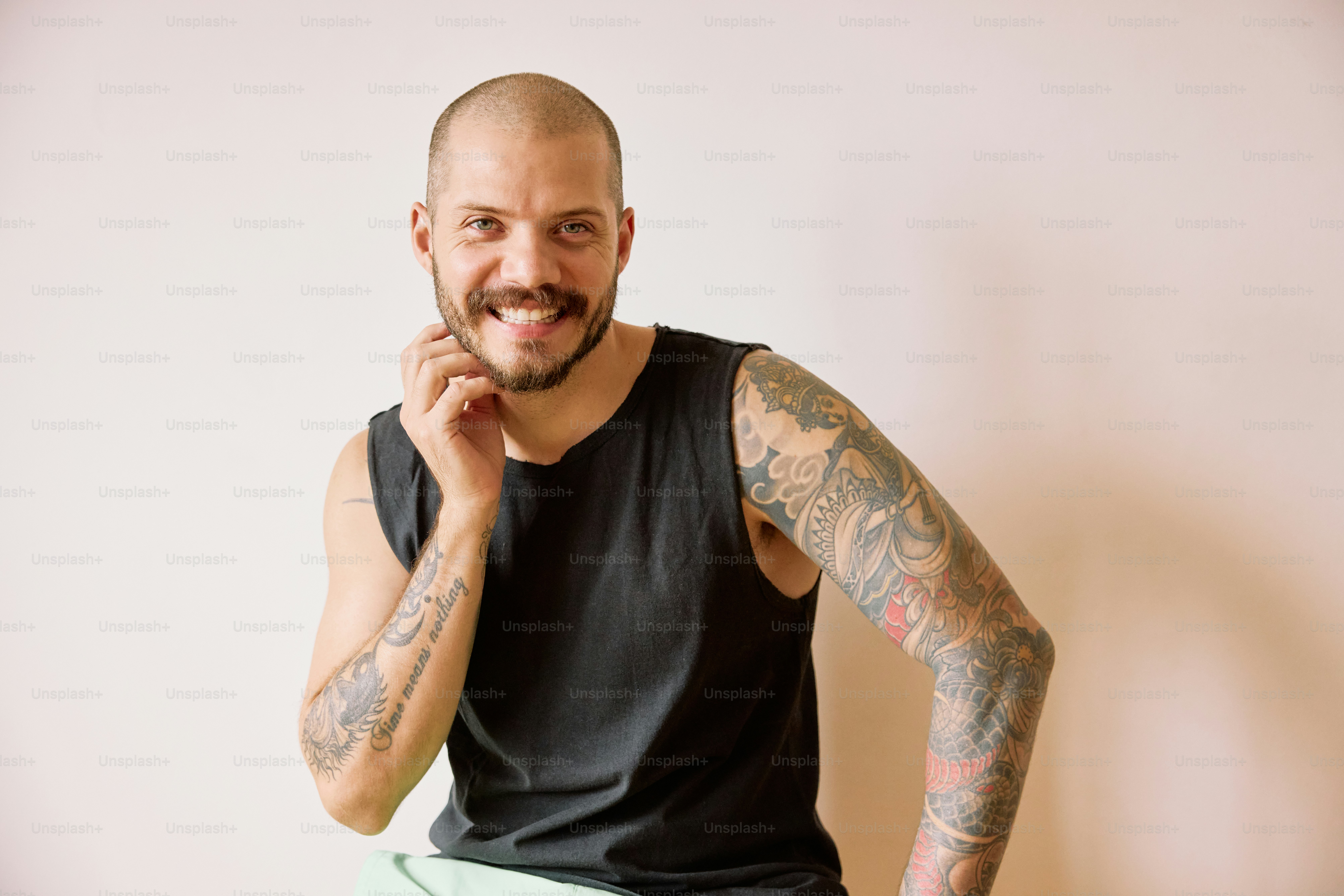 a man with tattoos sitting on a stool
