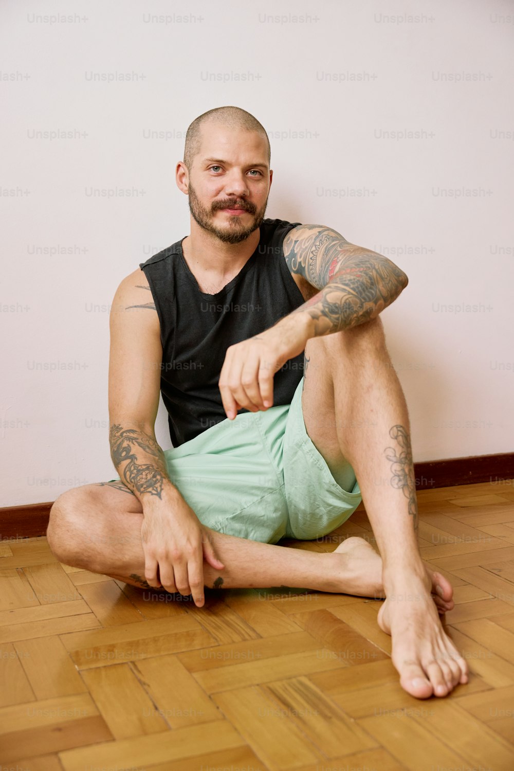 un uomo con tatuaggi seduto sul pavimento