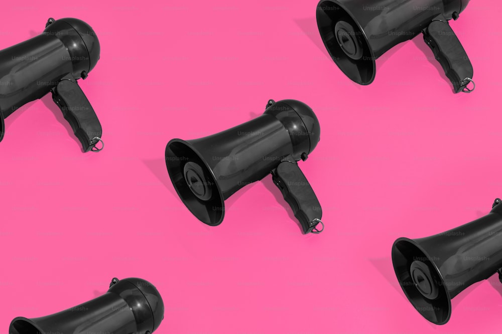 a group of black speakers sitting on top of a pink surface