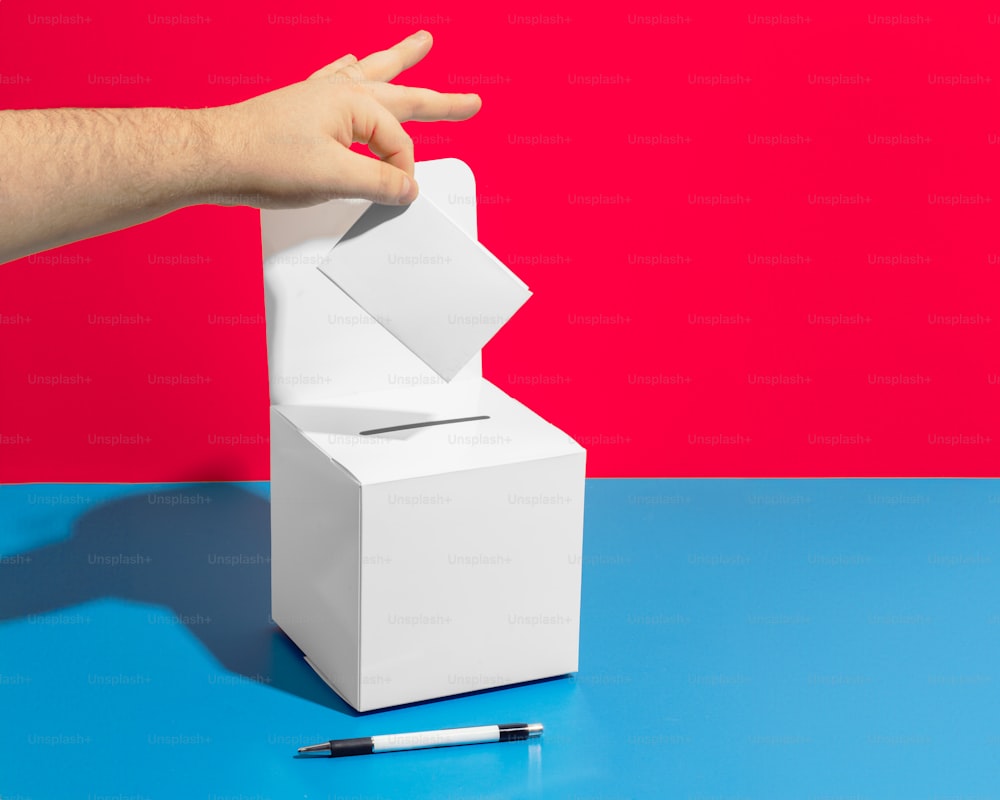 a hand reaching into a white box with a piece of paper sticking out of it
