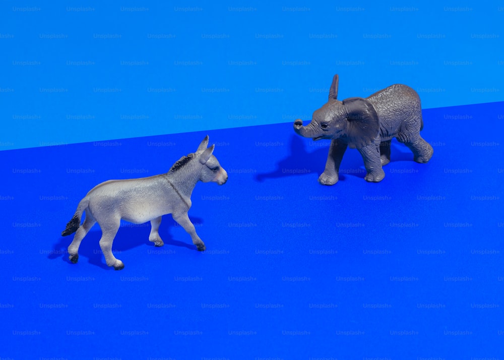 a couple of toy animals standing on top of a blue surface