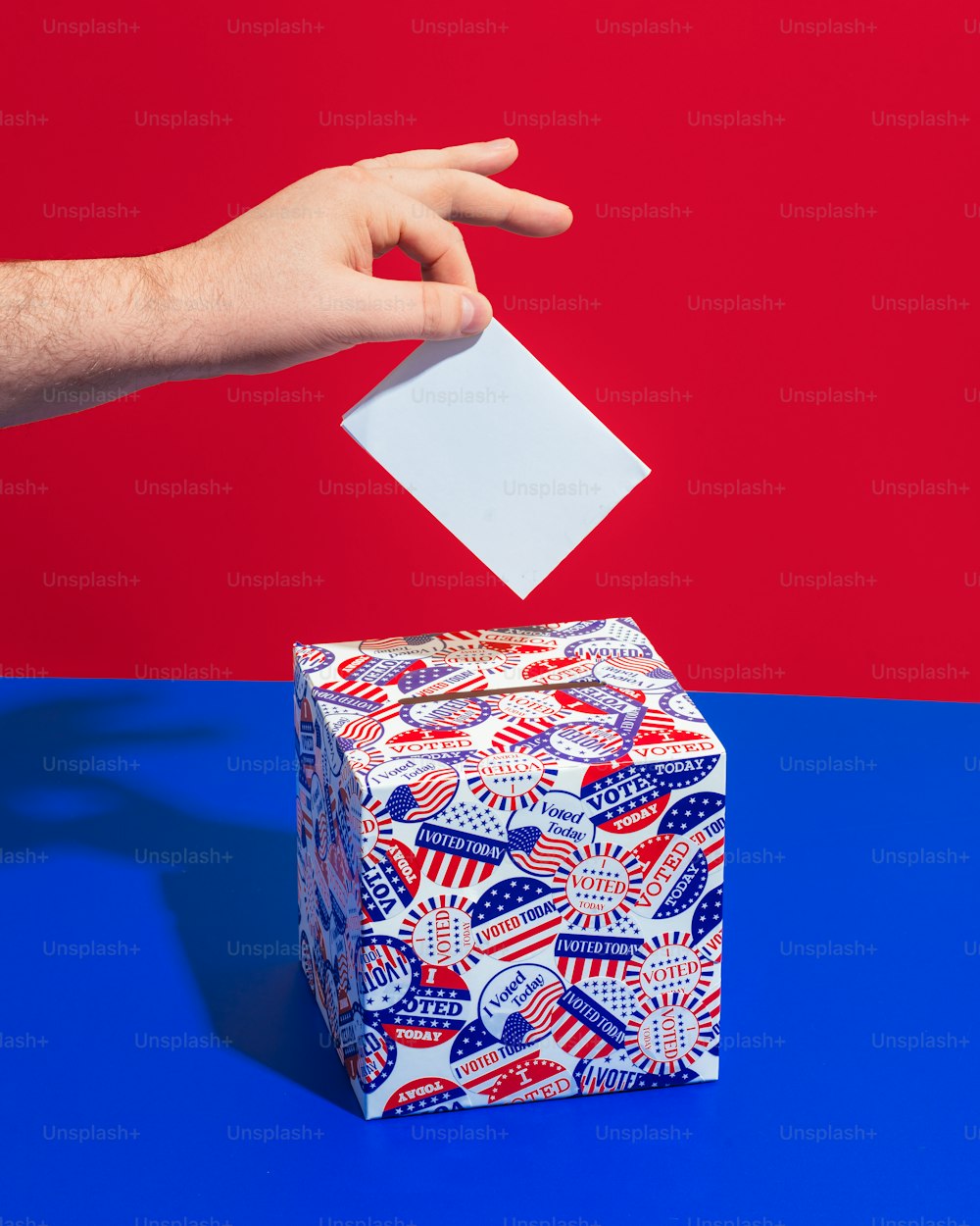 a person's hand throwing a piece of paper into a gift box